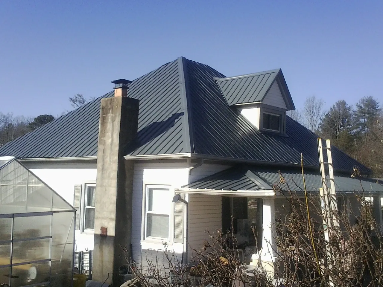 Dark blue standing seam metal roof on a white farmhouse with dormer — Slate & Tile Roof Repair by Roofing Brothers in Cottekill