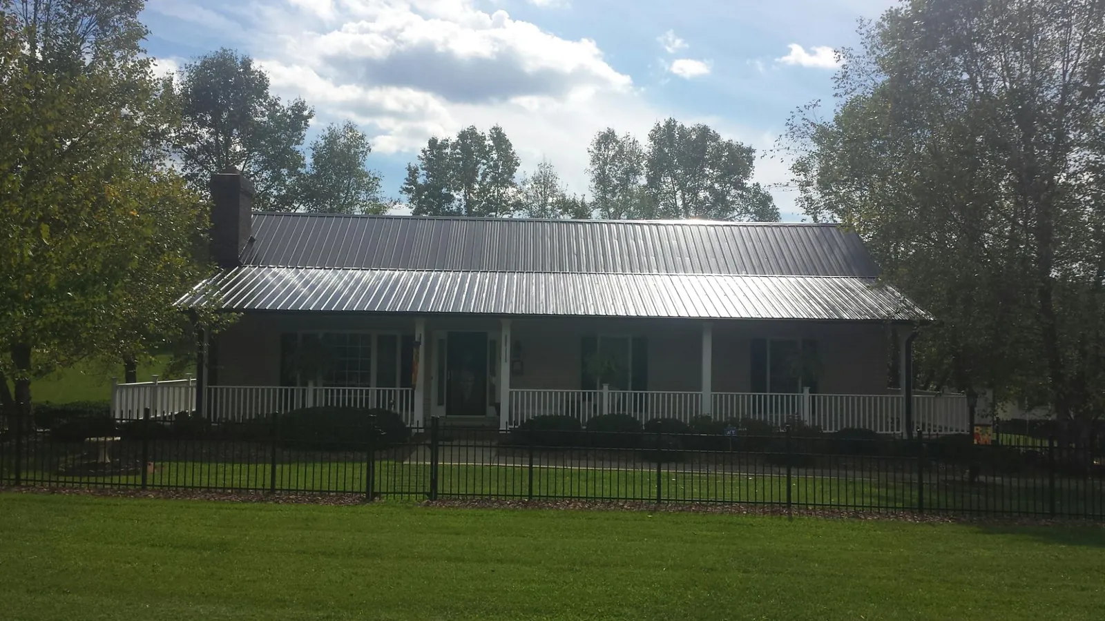 Gray metal roof on a brick ranch with a full width front porch — Gutter Guard Installation work by our crew in Cottekill