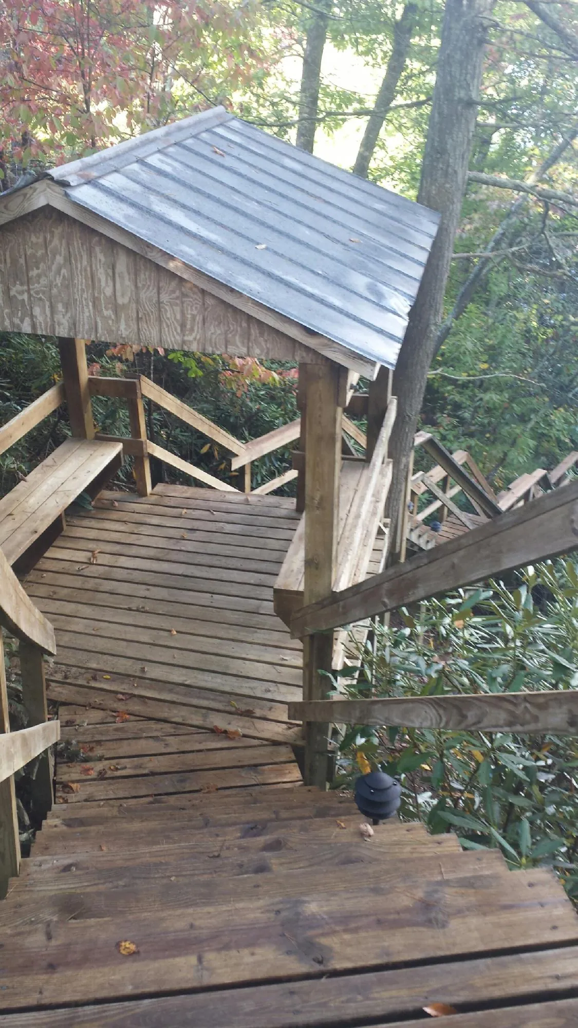 Metal roofed shelter over wooden steps on a wooded walkway — Skylight Repair & Installation work by our crew in Cottekill