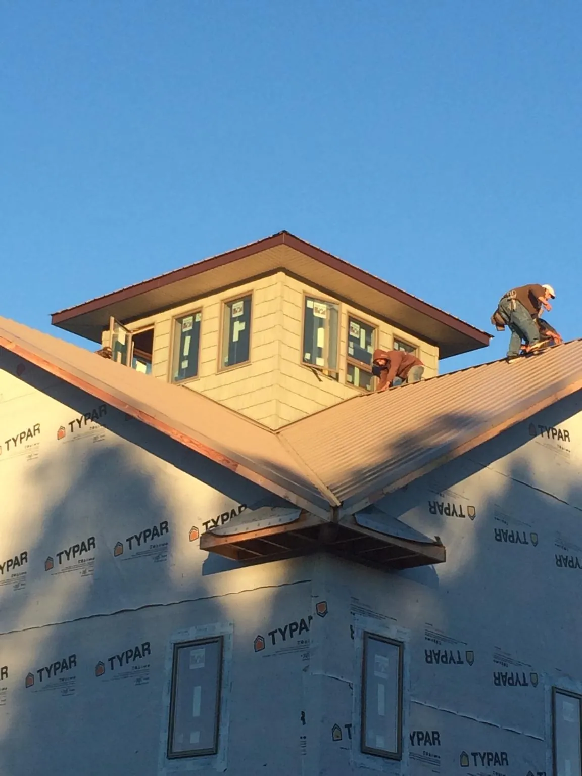 Roofers working around a rooftop cupola on a new metal roof at sunset — Roof Waterproofing in Cottekill by Roofing Brothers